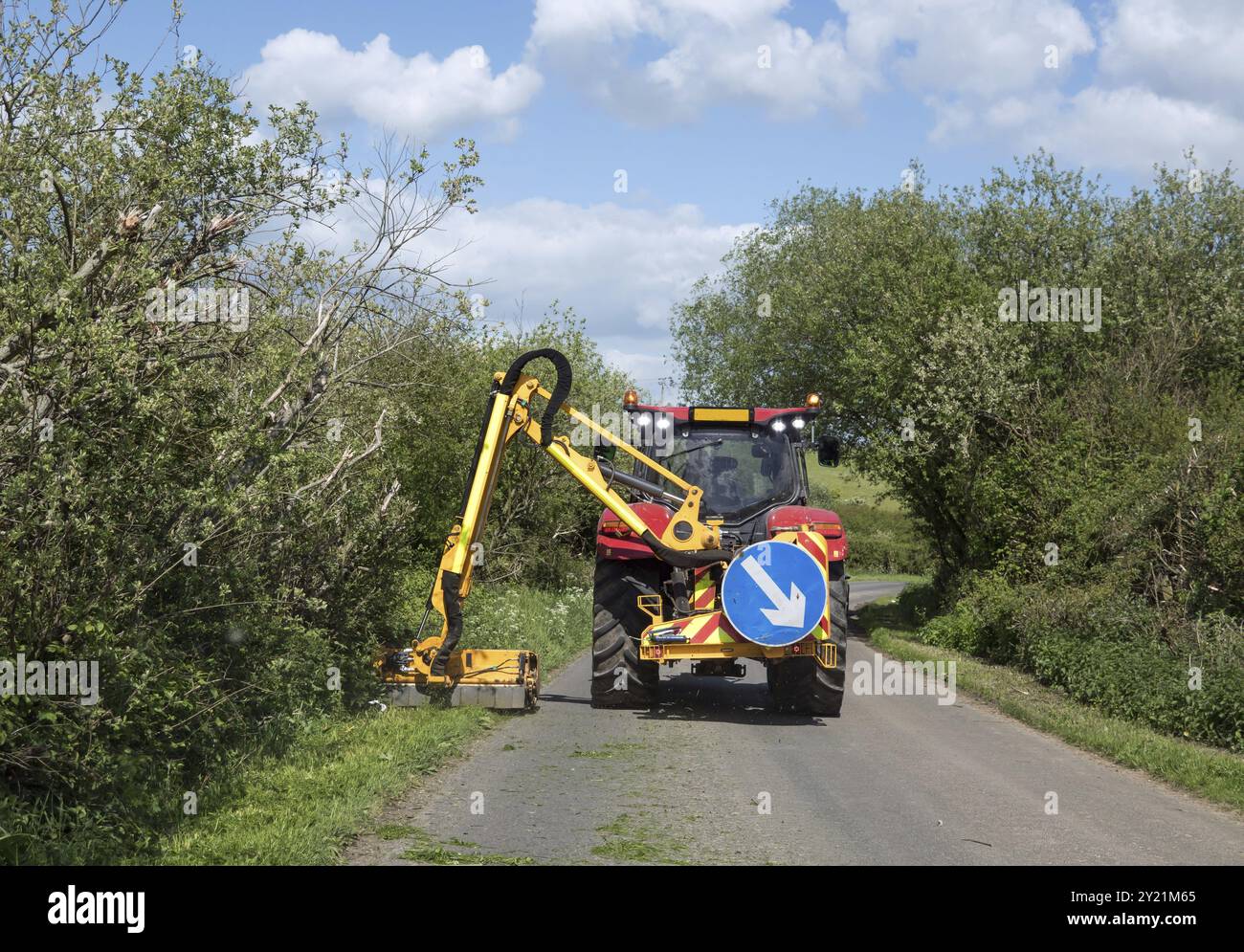 Durante la primavera, l'erba verrebbe tagliata da un grande trattore falciante nella corsia di campagna del Sussex Foto Stock