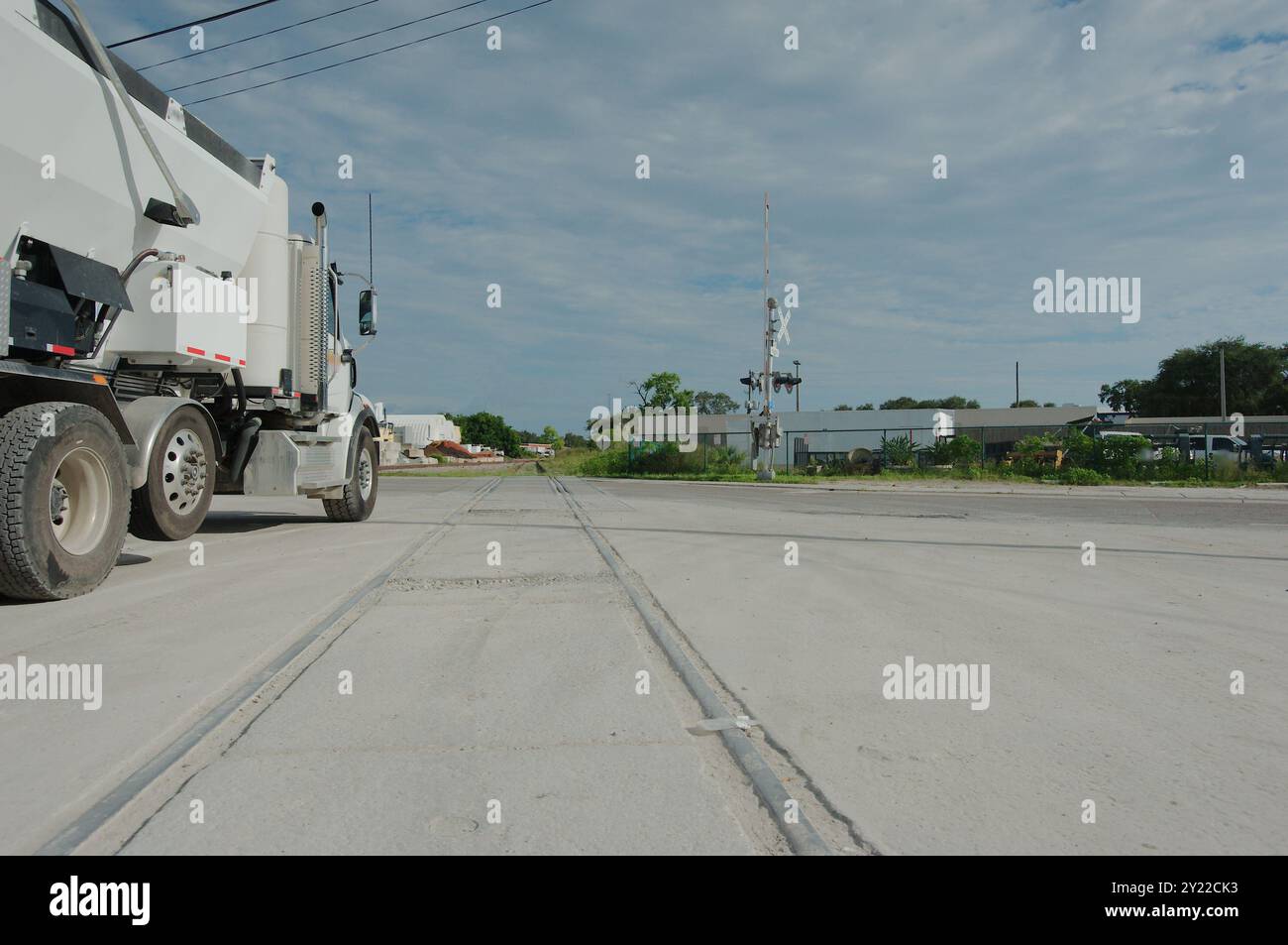 Le linee principali della vista laterale dei binari ferroviari di un grande camion di cemento bianco nel tardo pomeriggio con cielo blu e nuvole bianche nel retro. Binari ferroviari Foto Stock