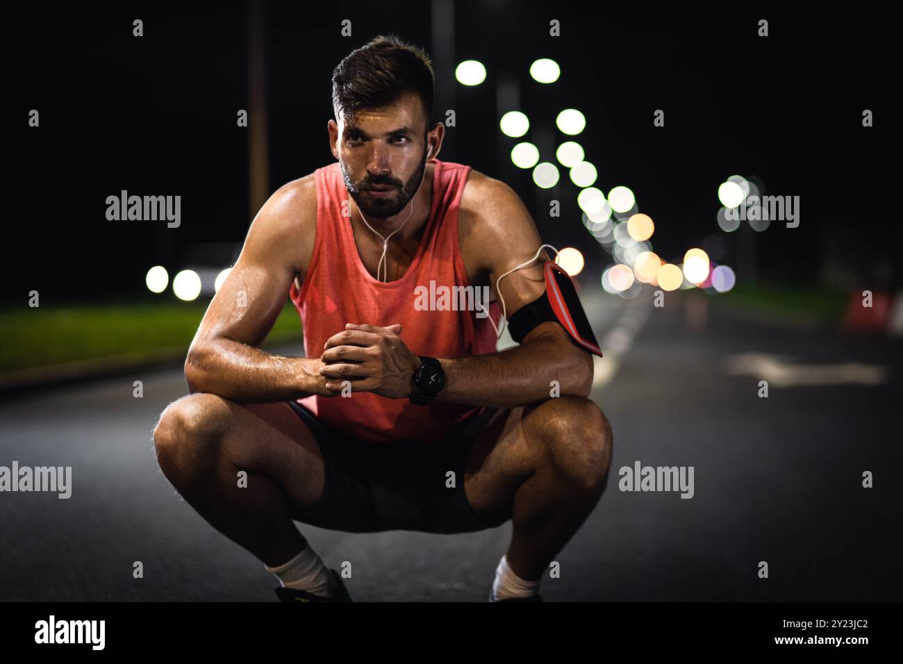 Runner maschile che riposa dopo l'allenamento notturno in città. Foto Stock