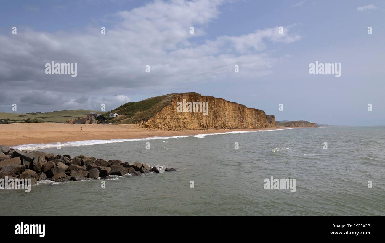 Affacciato su un mare calmo alle scogliere di arenaria di East Beach a West Bay a Bridport, Dorset, Regno Unito. Le scogliere si innalzano per 50 metri verticalmente Foto Stock