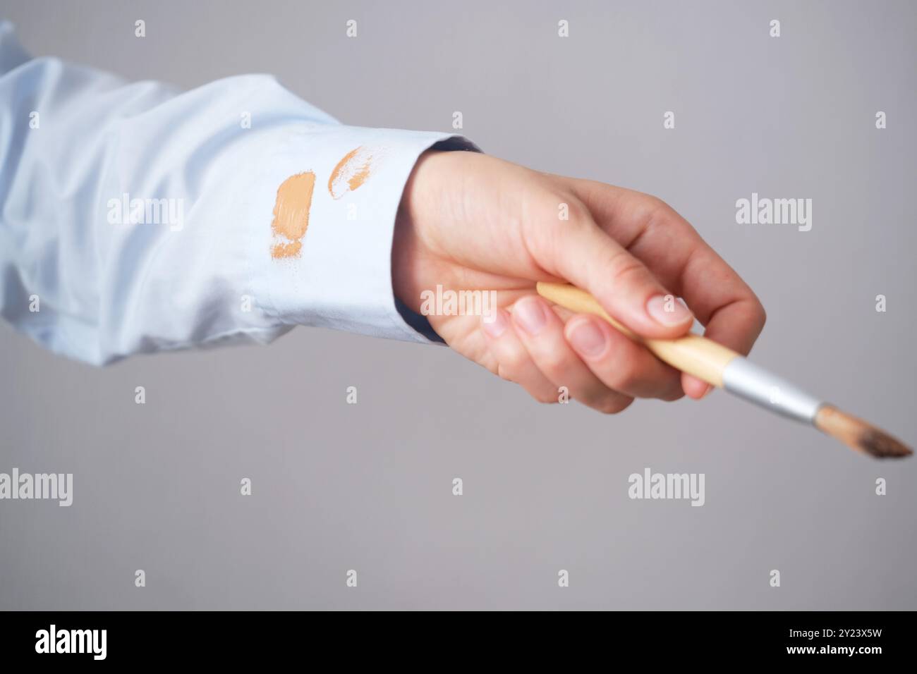 Donna che applica le fondamenta con una spazzola indossando una camicia azzurra in una stanza ben illuminata durante il giorno. concetto di colorazione per la vita quotidiana. Alta qualità p Foto Stock