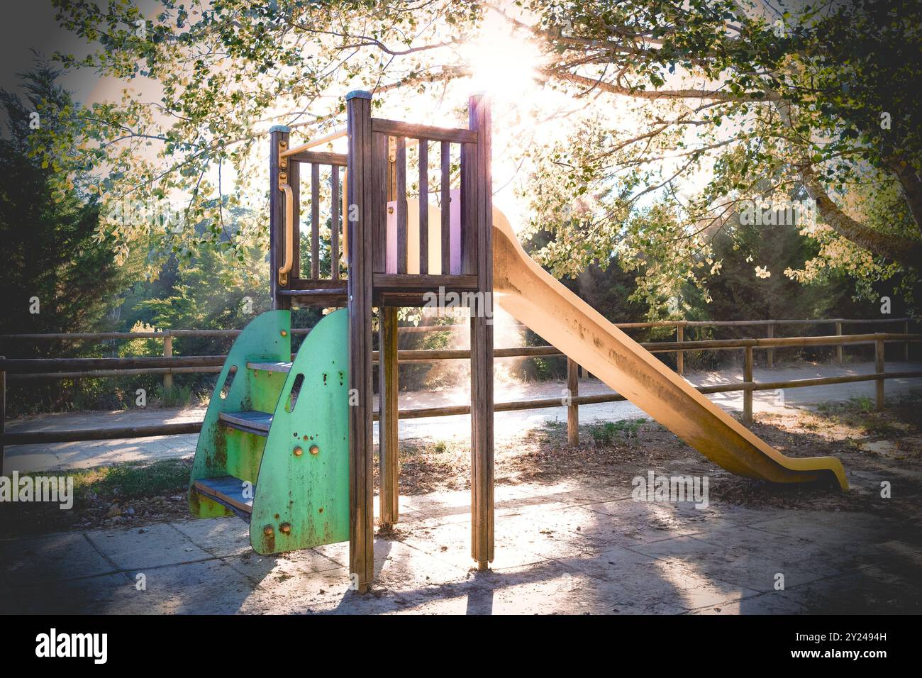 Parco giochi tra gli alberi della foresta, con luce del tramonto e raggi di sole tra i rami. Parco giochi per bambini nel parco. Foto Stock