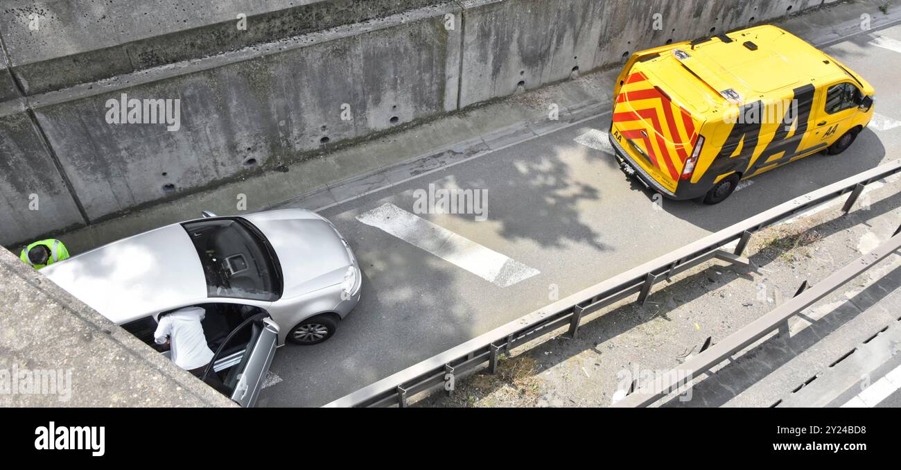 L'auto in avaria è stata spostata da sotto il ponte stradale giacca gialla il meccanico AA completa l'ingresso del veicolo M25 sulla spalla rigida dell'autostrada Essex Inghilterra Regno Unito Foto Stock