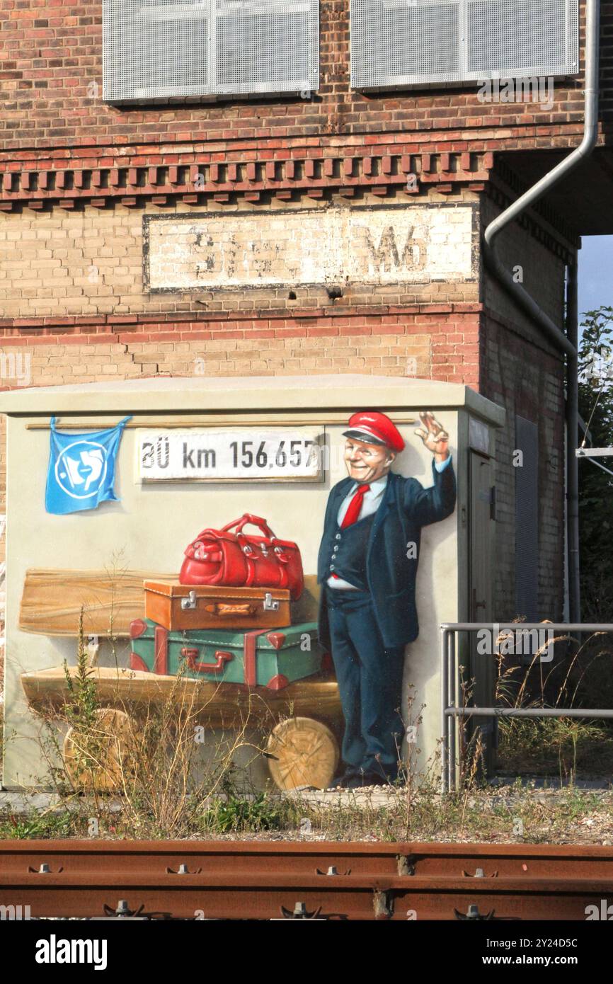 Blick am Sonntag 08.09.2024 a Malchin Landkreis Mecklenburgische Seenplatte auf das ehemalige Relaisgebäude der Deutschen Bahn. Die Deutsche Bahn treibt sein Jahren ihre Mobilitätsoffensive weiter voran. Im Zuge dessen wurden in der zurückliegenden Zeit auch die Abläufe rund um den örtlichen Bahnhof automatisiert. Damit haben auch die historischen Stellwerke in der Stadt inzwischen ihre Bedeutung verloren. Suora wurde ein Gebäudeteil mit einem Graffiti verziert das einen freundlichen Bahnmitarbeiter zeigt. Dieses kann jedoch nicht darüber hinwegtäuschen, dass bei der Deutschen Bahn noch immer e Foto Stock