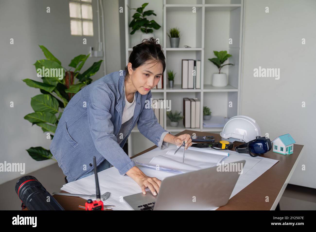 Ingegnere che lavora su progetti con un computer portatile in ufficio Foto Stock