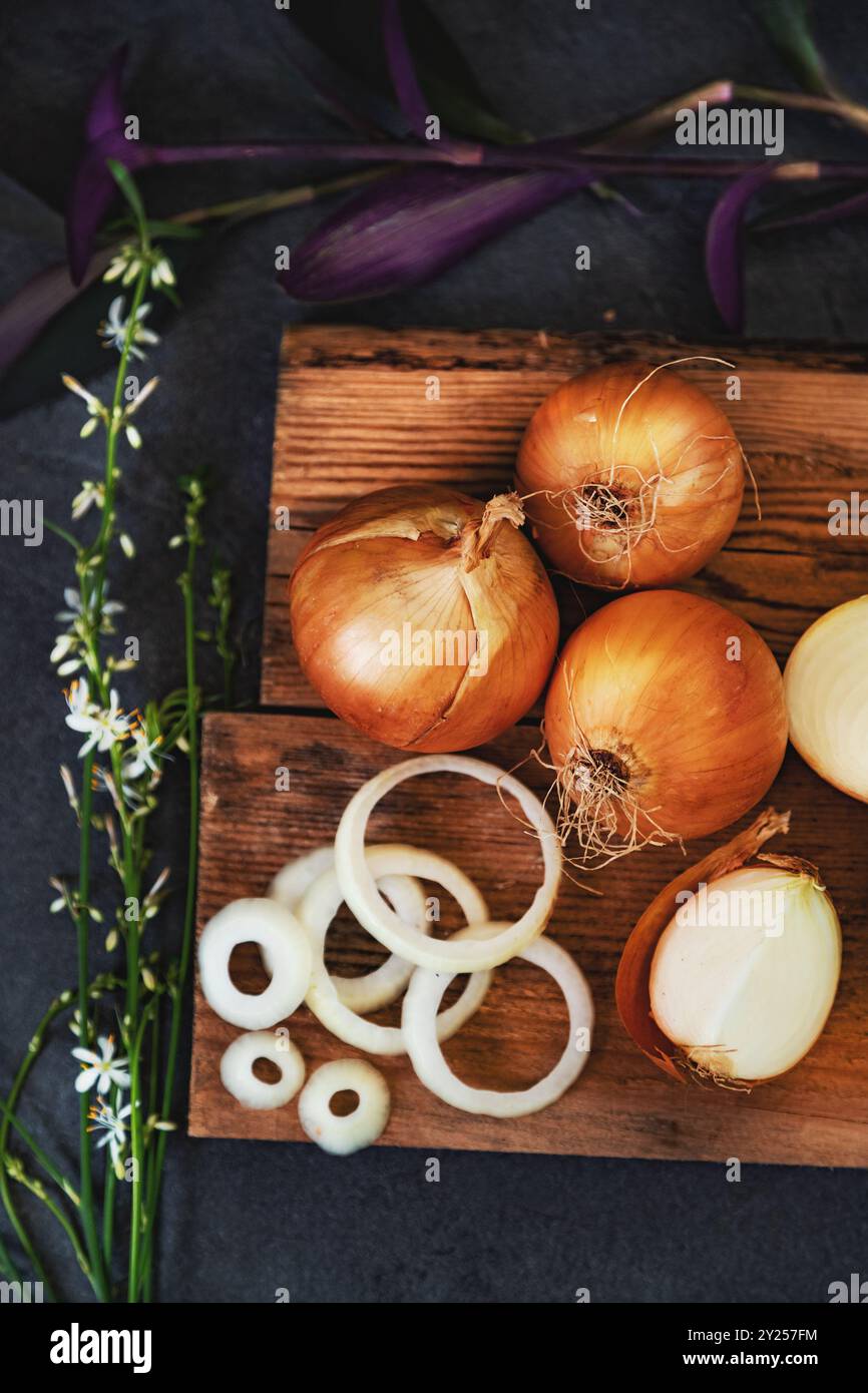 Un sacco di cipolle in un cestino e piatti su un fondo scuro ed elegante struttura scura. Foto Stock