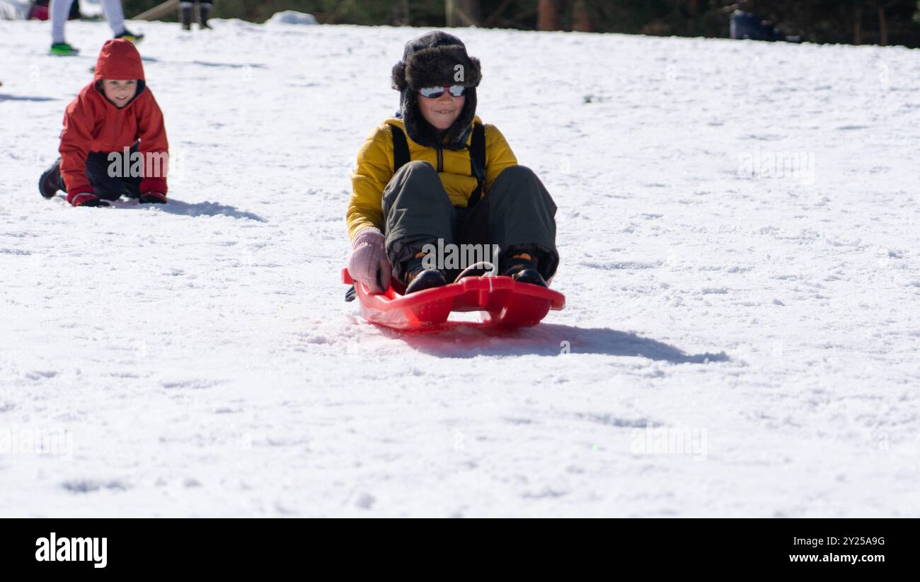 Bambini che giocano con una slitta nella neve in natura Foto Stock