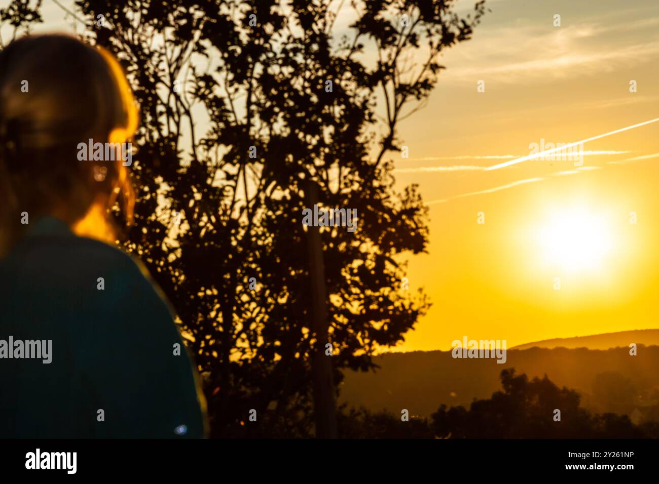 Una donna sta su una collina e guarda l'alba. Sfondo defocalizzato donna che guarda l'alba. Foto Stock