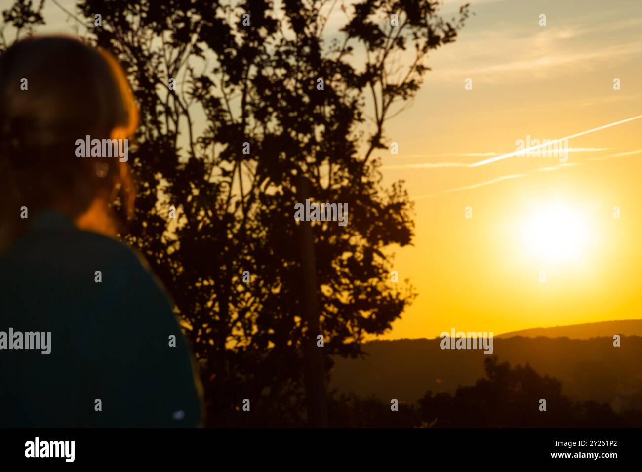 Una donna sta su una collina e guarda l'alba. Sfondo defocalizzato donna che guarda l'alba. Foto Stock