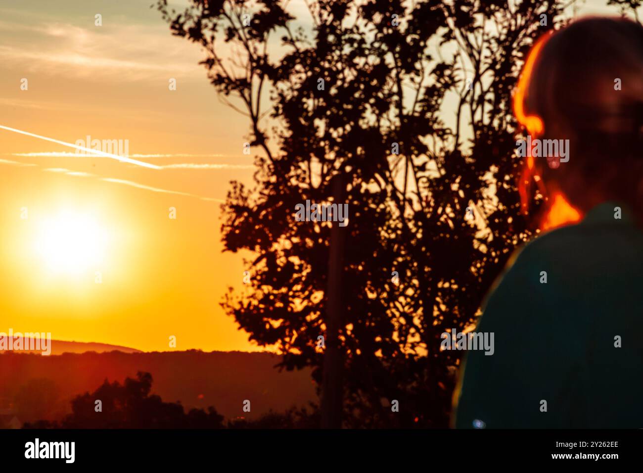 Una donna sta su una collina e guarda l'alba. Sfondo defocalizzato donna che guarda l'alba. Foto Stock