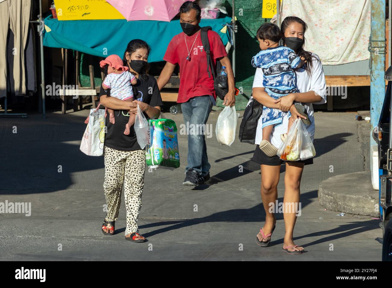 SAMUT PRAKAN, THAILANDIA, FEB 08 2023, le donne trasportano bambini tra le braccia per strada Foto Stock