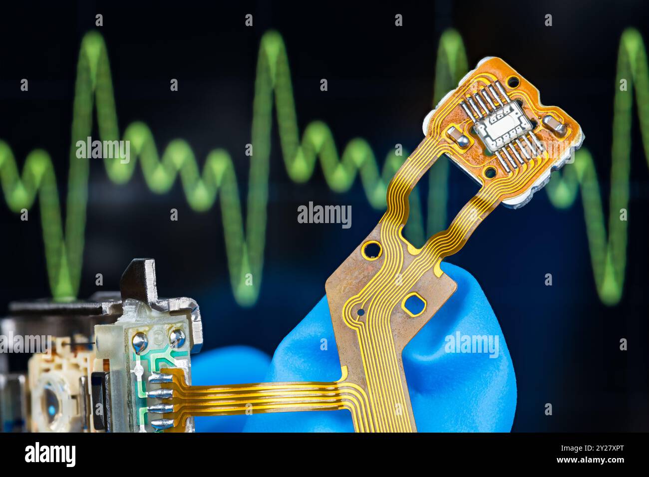 Circuito integrato di sensore ottico, lente o cavo piatto flessibile a disposizione del tecnico in laboratorio tecnologico con sfondo dello schermo dell'oscilloscopio elettronico. Foto Stock