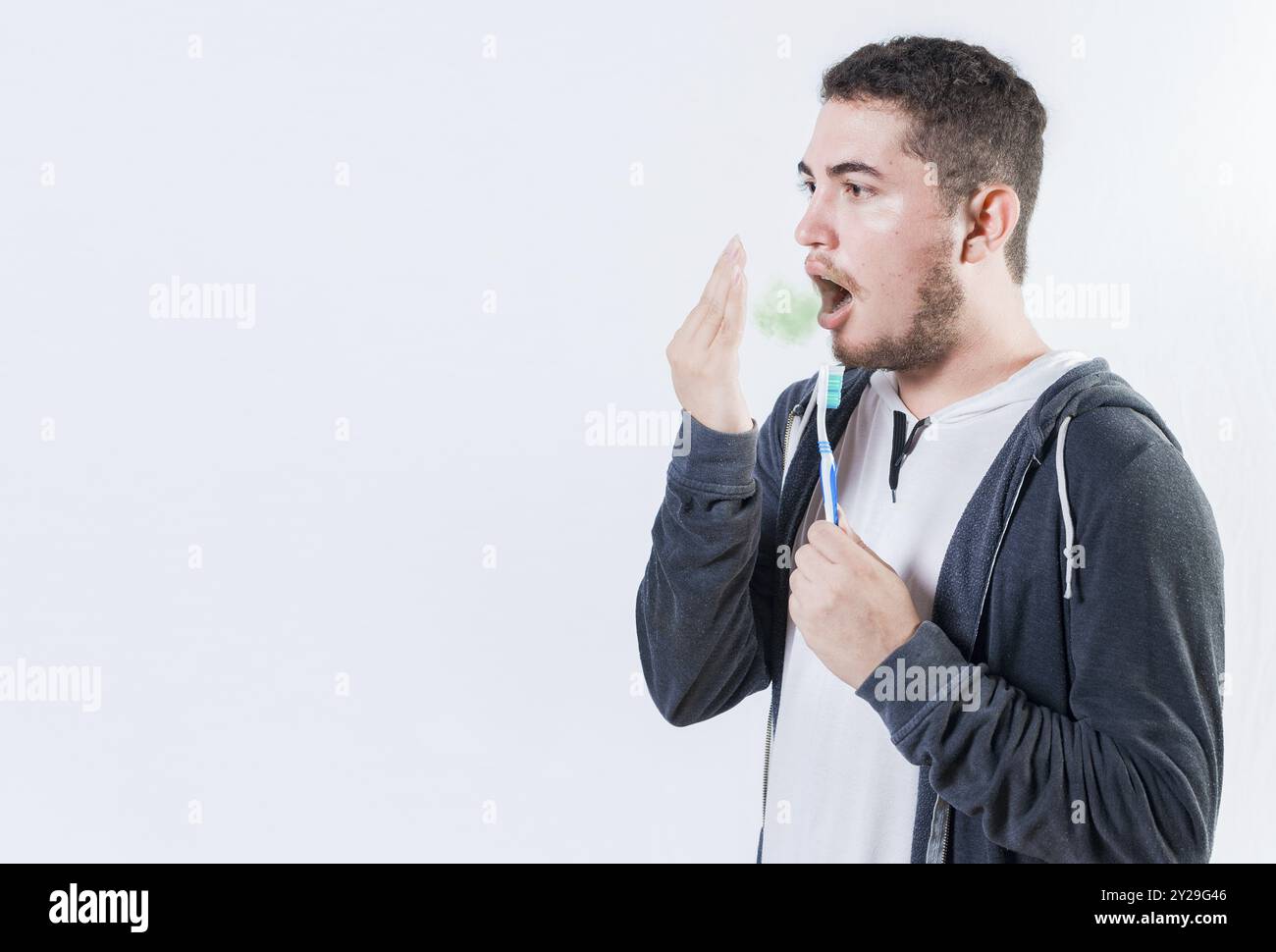 Persona che tiene la spazzola con problema di alito cattivo isolato. Uomo che tiene la spazzola a controllare l'alito cattivo Foto Stock