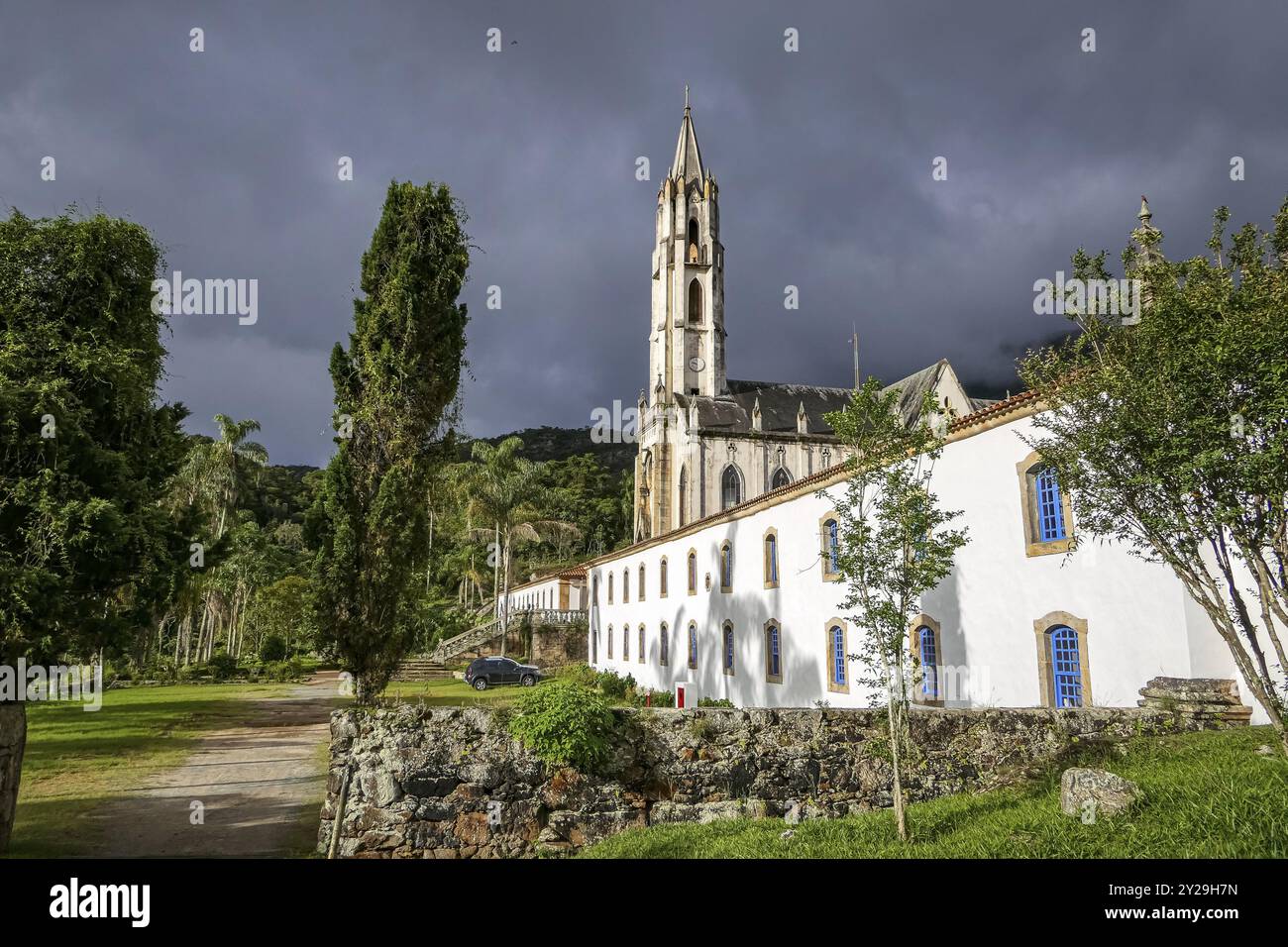 Ammira la chiesa e gli edifici alla luce del sole con nuvole grigie sullo sfondo, il Santuario di Caraca, Minas Gerais, Brasile, Sud America Foto Stock