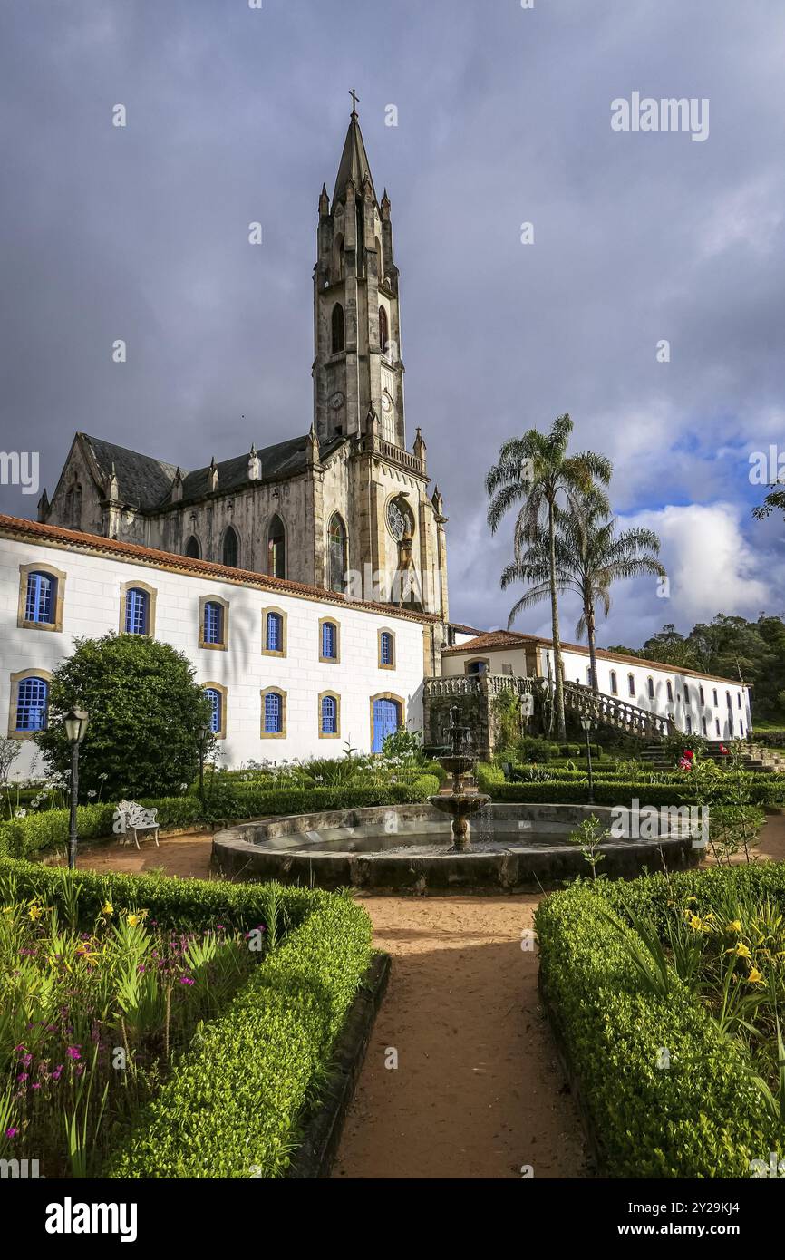 Ammira la chiesa e gli edifici alla luce del sole con nuvole grigie sullo sfondo, il Santuario di Caraca, Minas Gerais, Brasile, Sud America Foto Stock