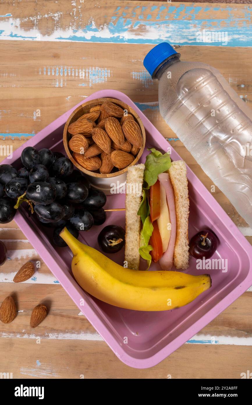 Presentazione del pranzo a scuola. Vista dall'alto che mostra un pranzo al sacco ecologico pieno di cibi nutrienti, proteine, frutta e cereali Foto Stock