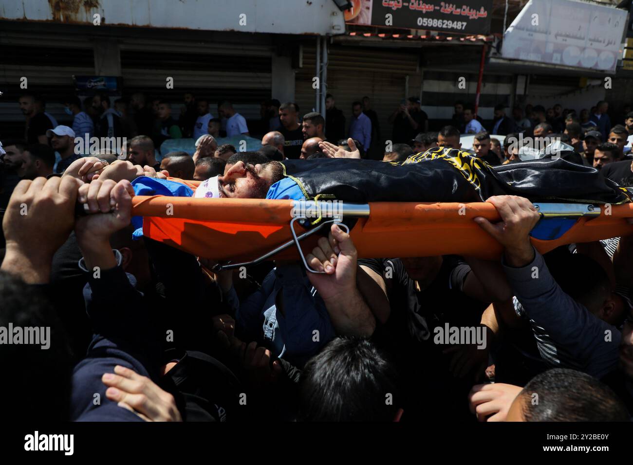 Jenin, Cisgiordania, Palestina. 9 aprile 2022. I palestinesi nel campo profughi di Jenin, nella Cisgiordania settentrionale, trasportano il corpo di Ahmad al-Saadi, 23 anni, ucciso durante un raid israeliano su larga scala sul campo profughi di Jenin nella Cisgiordania settentrionale. Si ritiene che al-Saadi sia stato affiliato al movimento della Jihad islamica palestinese. Almeno altri 13 palestinesi hanno subito ferite da proiettile, tra cui una donna di 19 anni, durante i pesanti scontri avvenuti durante il raid. Il raid segue l'uccisione da parte dei soldati israeliani di venerdì di Raad Hazem, 28 anni, presumibilmente dietro a una sparatoria letale Foto Stock