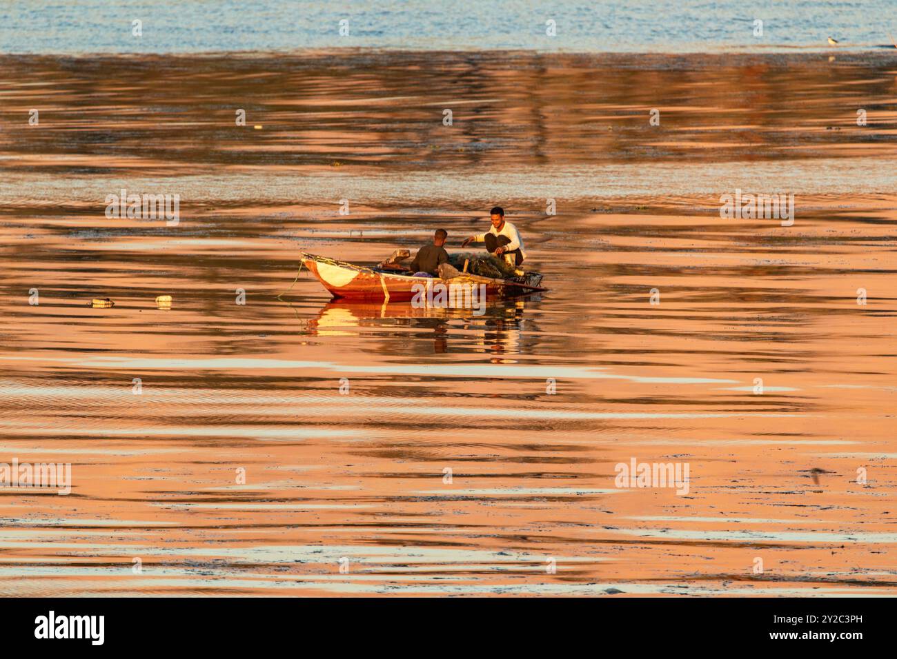 Luxor, Egitto, 16 gennaio 2024: Mentre il sole tramonta all'orizzonte, proiettando un bagliore arancione sul fiume Nilo, i pescatori egiziani continuano l'antica storia. Foto Stock