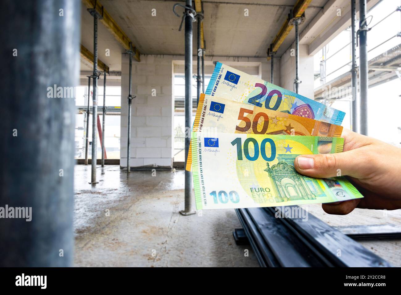 Tenere a mano le banconote in euro davanti all'interno di un cantiere edile Foto Stock