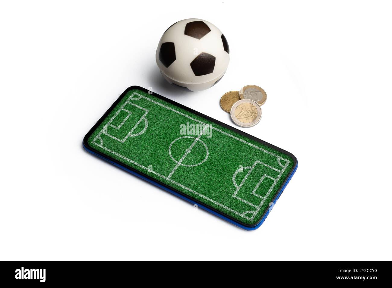 Concetto di scommessa sul calcio: Smartphone con campo di calcio sullo schermo lungo un pallone da calcio e alcune monete isolate Foto Stock