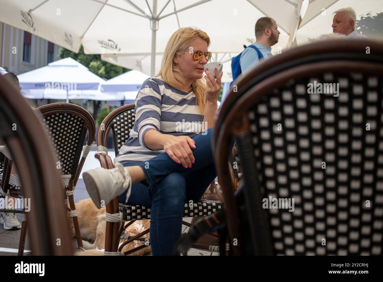 Belgrado, Serbia, 18 maggio 2024: Una donna assaggia un espresso in un caffè all'aperto a Zemun. Foto Stock