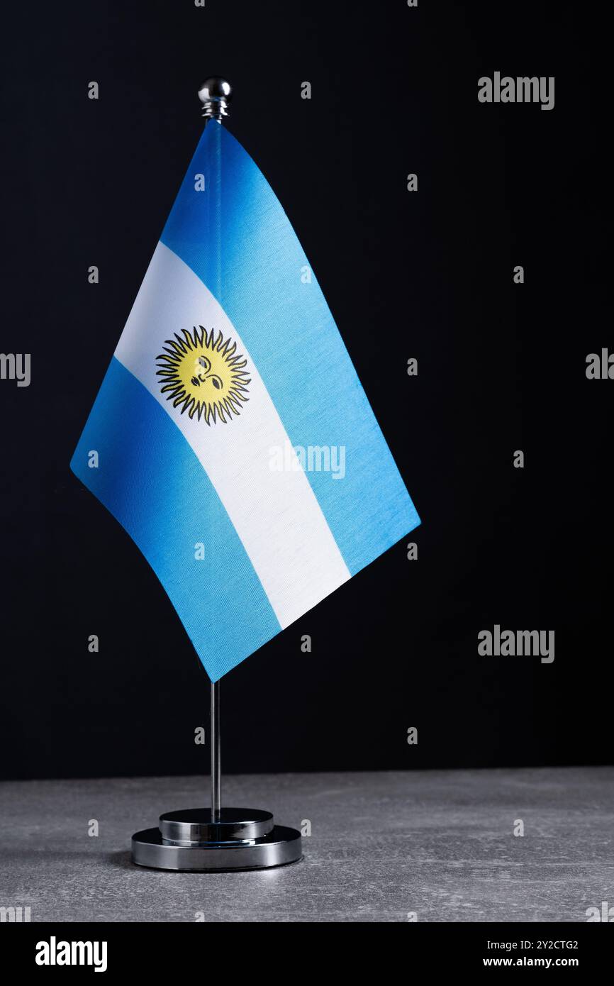 Bandiera Argentina su asta in metallo su tavolo in cemento grigio Foto Stock