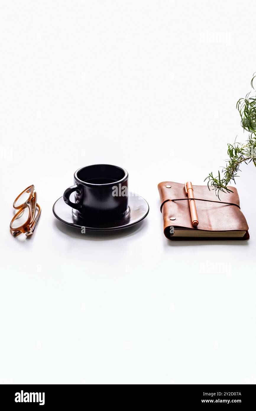 Oggetti essenziali per l'ufficio con tazza da caffè, bicchieri, notebook e pianta su una scrivania bianca. Foto Stock Oggetti essenziali per l'ufficio con tazza da caffè, bicchieri, notebook e pianta su una scrivania bianca. Foto Stock
