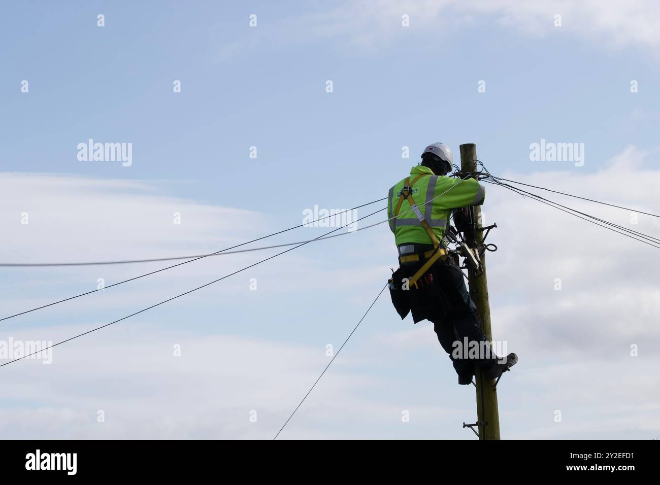 Tecnico telefonico Openreach in cima a un palo del telegrafo o a linee telefoniche di cablaggio di un palo Foto Stock