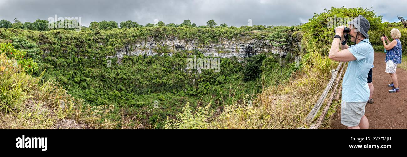 I turisti che guardano attraverso un binocolo al punto di osservazione sul bordo di uno dei crateri vulcanici gemelli, l'isola di Santa cruz, le Galapagos Foto Stock