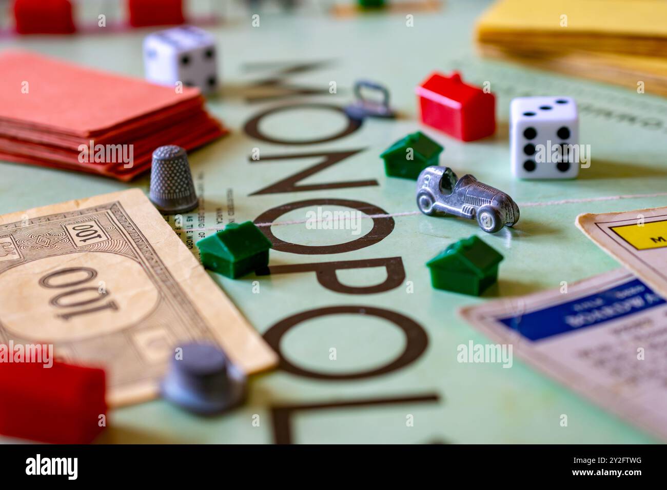 Un tabellone monopolio cosparso di pezzi da gioco, tra cui denaro, case, hotel, dadi da marcatura scarpe, carte chance e community. Foto Stock