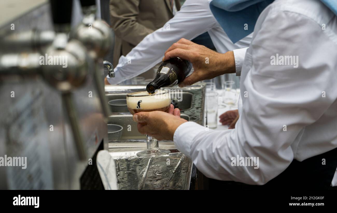 Creare la birra perfetta: Il barista prepara i bicchieri di birra in un matrimonio molto affollato Foto Stock