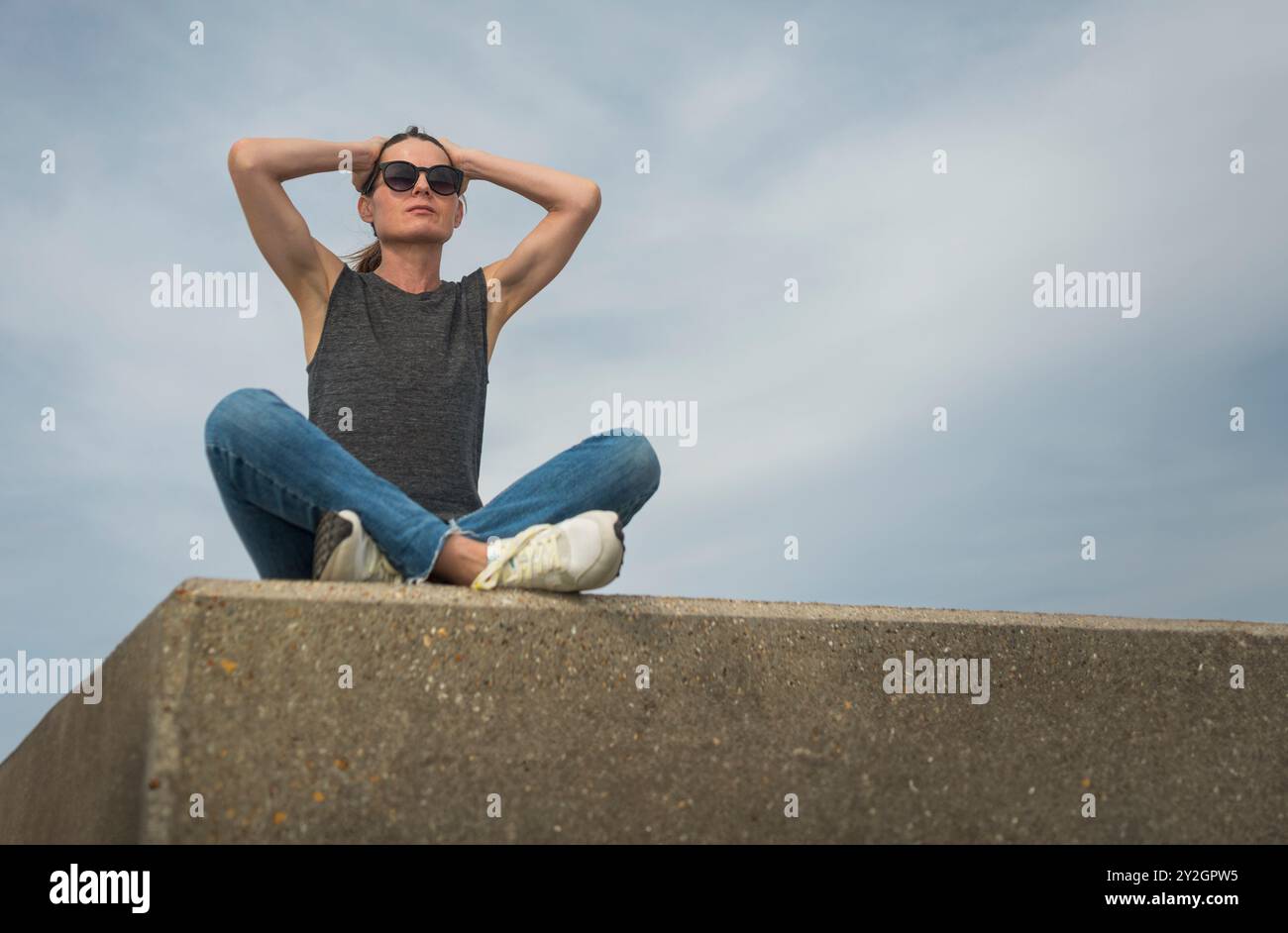 Donna seduta all'aperto con le mani sulla testa, concetto di stress emotivo Foto Stock