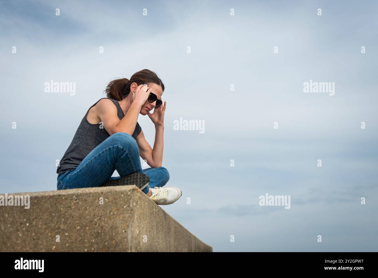 donna seduta all'aperto con la testa tra le mani, concetto di depressione Foto Stock
