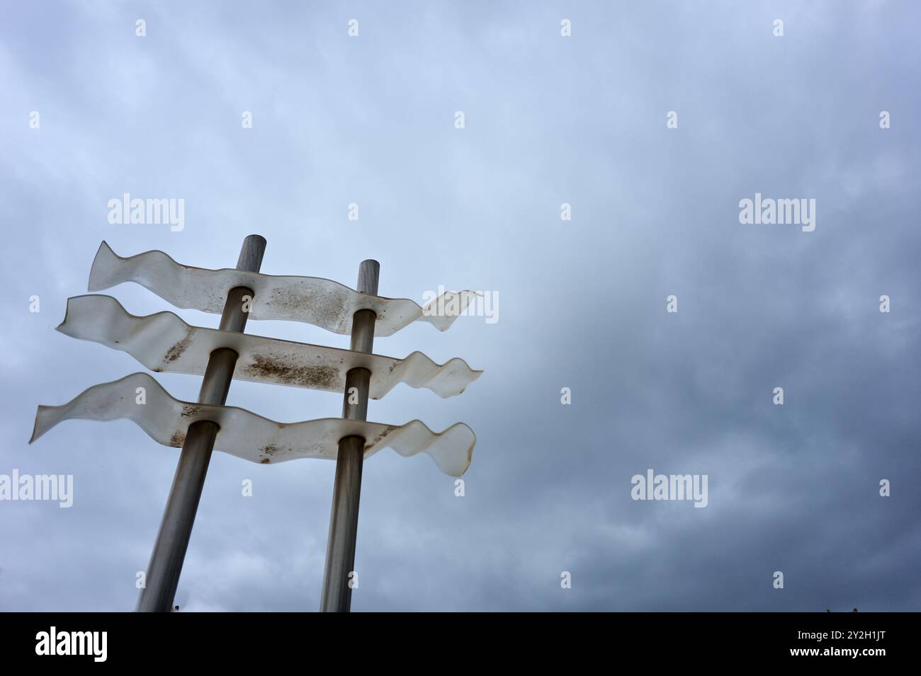 Installazione artistica di striscioni bianchi che sventolano su pali, evidenziando il contrasto tra la struttura artificiale e il cielo naturale. Foto Stock Installazione artistica di striscioni bianchi che sventolano su pali, evidenziando il contrasto tra la struttura artificiale e il cielo naturale. Foto Stock