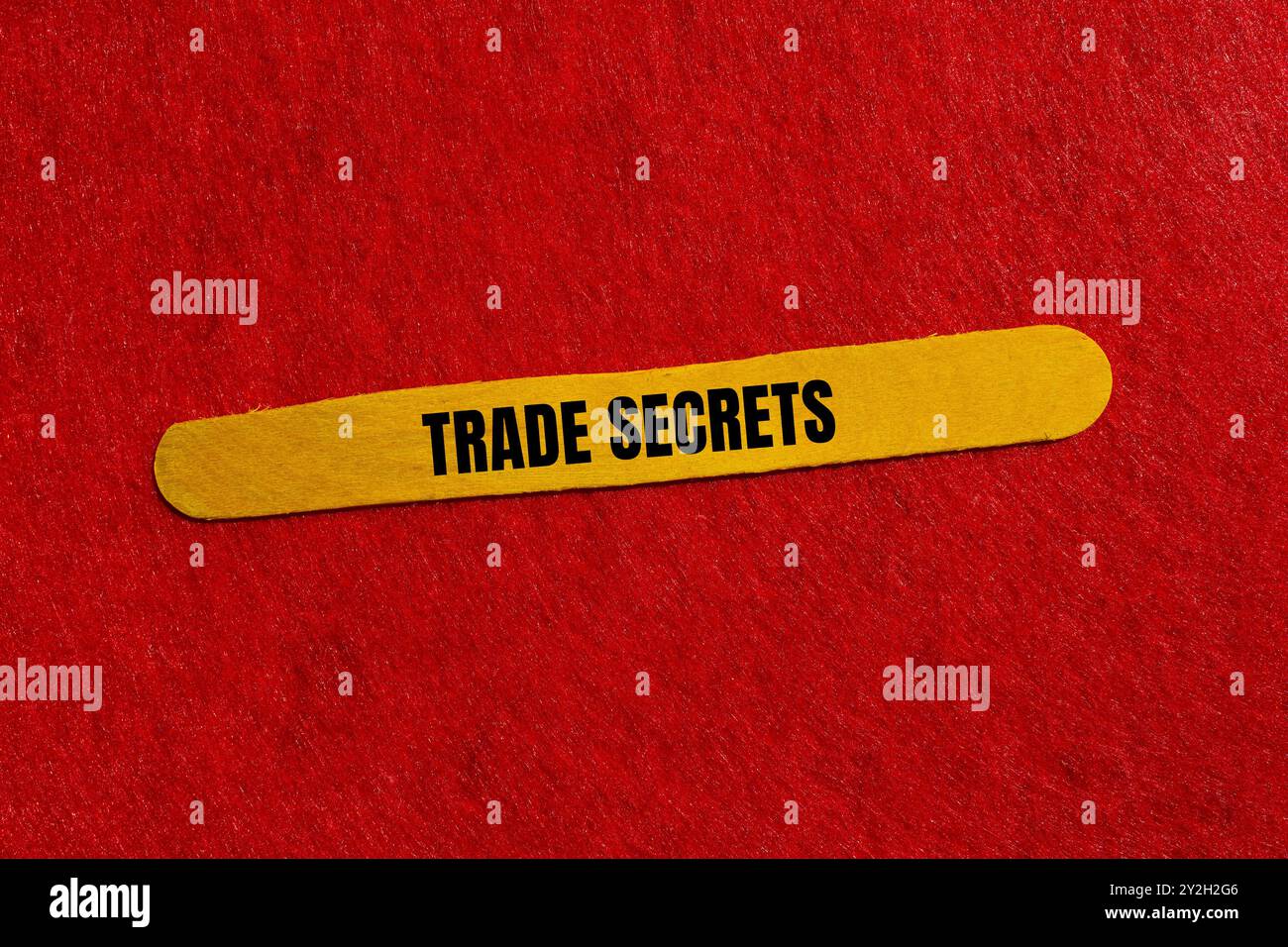 Messaggio segreto commerciale scritto su bastoncino di legno giallo con sfondo rosso. Simbolo dei segreti commerciali concettuali. Copia spazio. Foto Stock