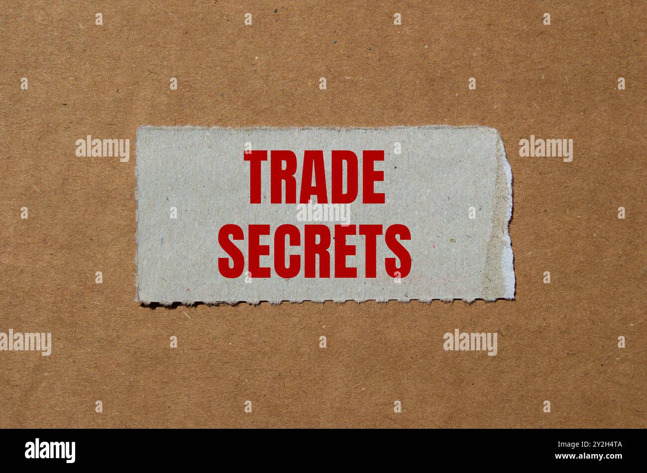 Messaggio segreto commerciale scritto su un pezzo di carta strappato con sfondo in cartone. Simbolo dei segreti commerciali concettuali. Copia spazio. Foto Stock