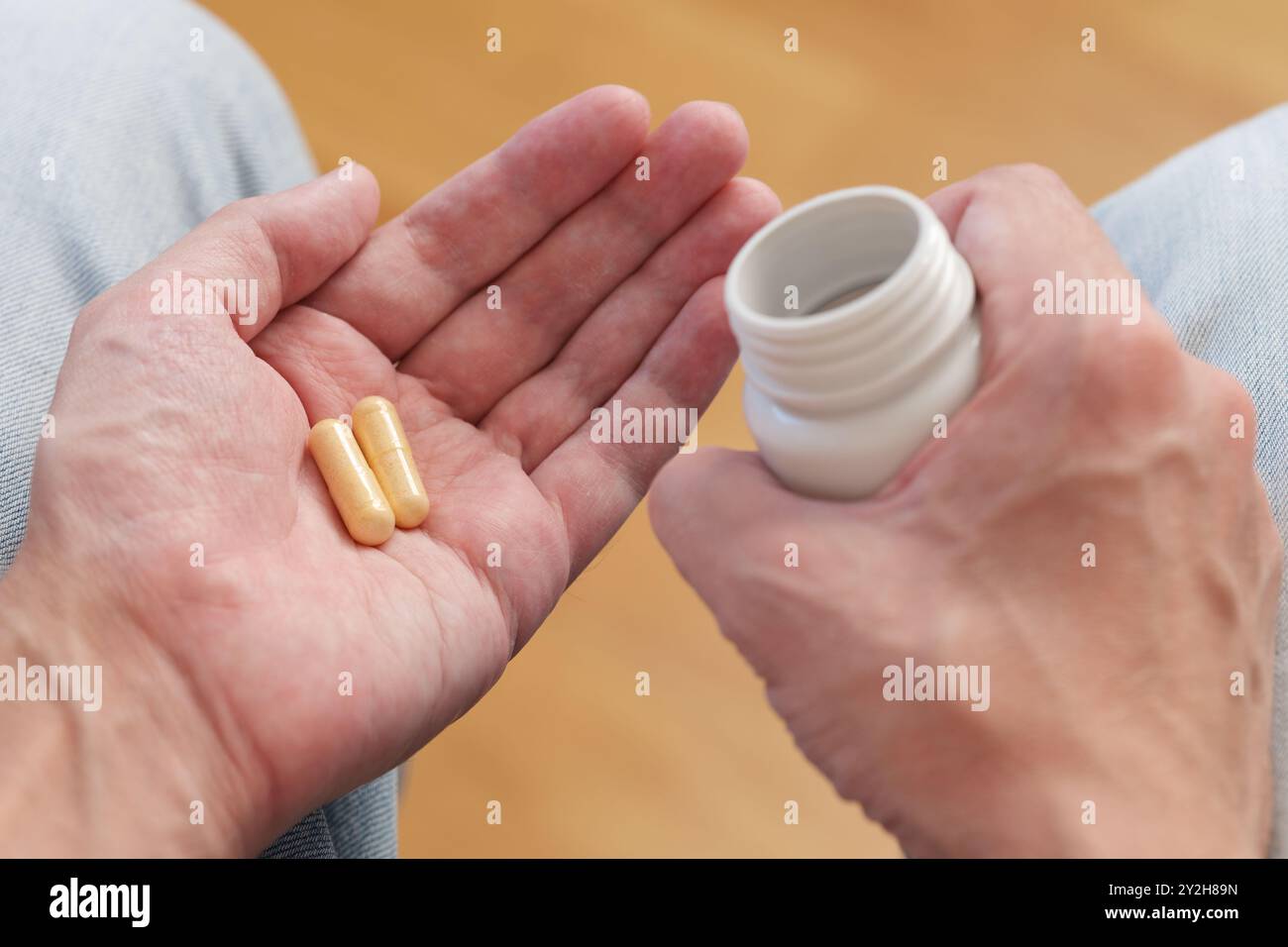 Un uomo ha versato pillole di vitamina B da una bottiglia di plastica nel palmo della sua mano. Foto Stock
