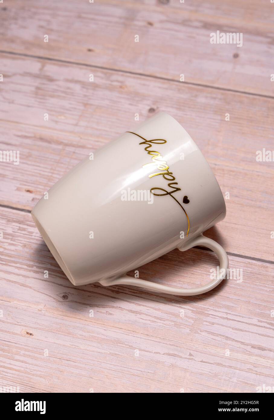 Una piacevole tazza in ceramica riempita di caffè accanto a un computer portatile su una scrivania in legno rustica, che rappresenta un'accogliente area di lavoro e la gioia di una pausa caffè Foto Stock