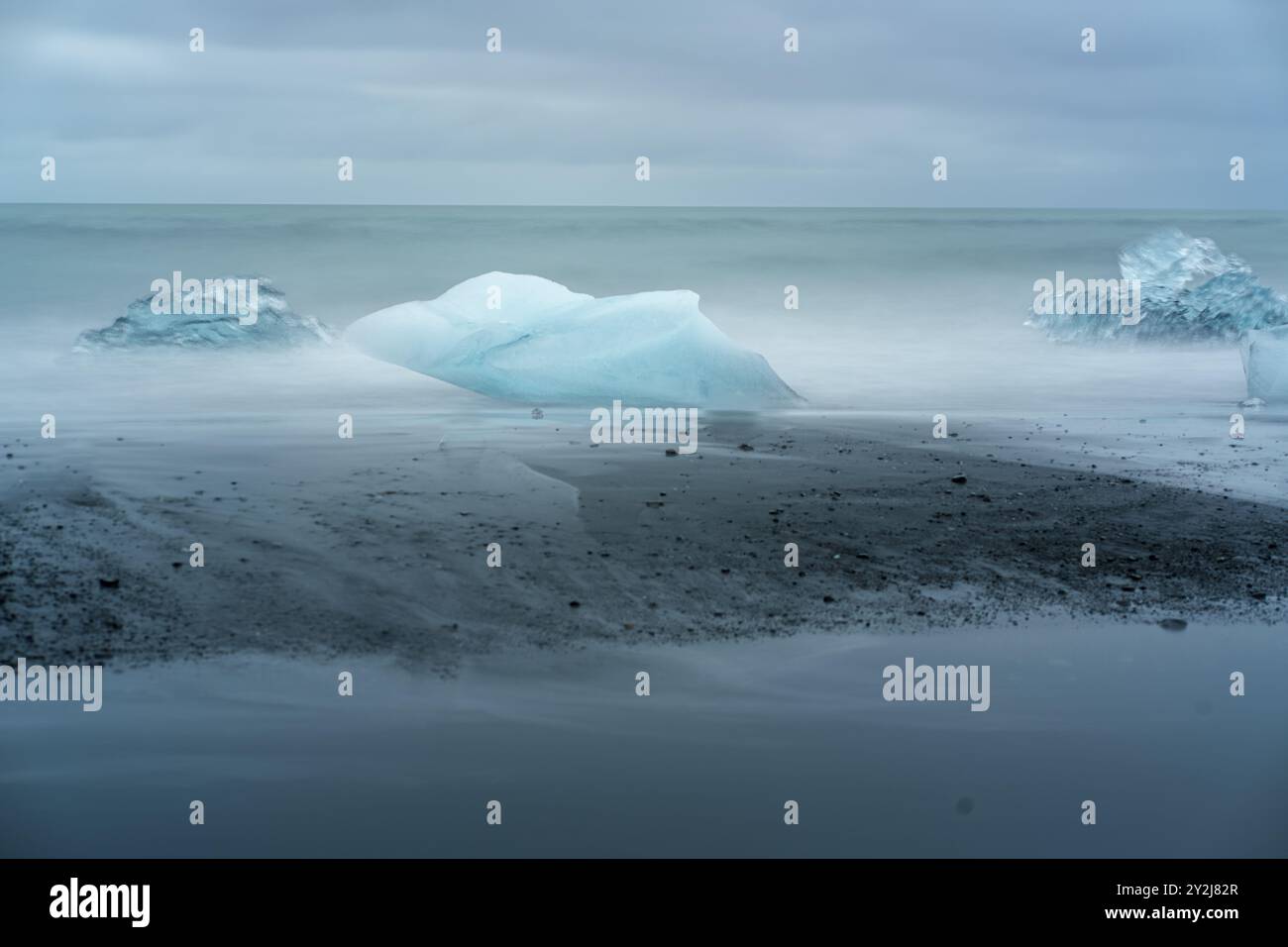 Una vista mozzafiato della Laguna del Ghiacciaio Jökulsárlón con iceberg galleggianti e le sabbie nere contrastanti di Diamond Beach in Islanda, sotto un'atmosfera spettacolare Foto Stock