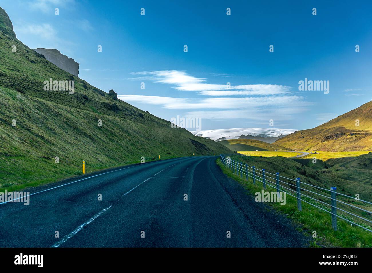 Montagne maestose con un massiccio ghiacciaio che scorre attraverso l'aspro paesaggio islandese sotto un cielo vibrante Foto Stock