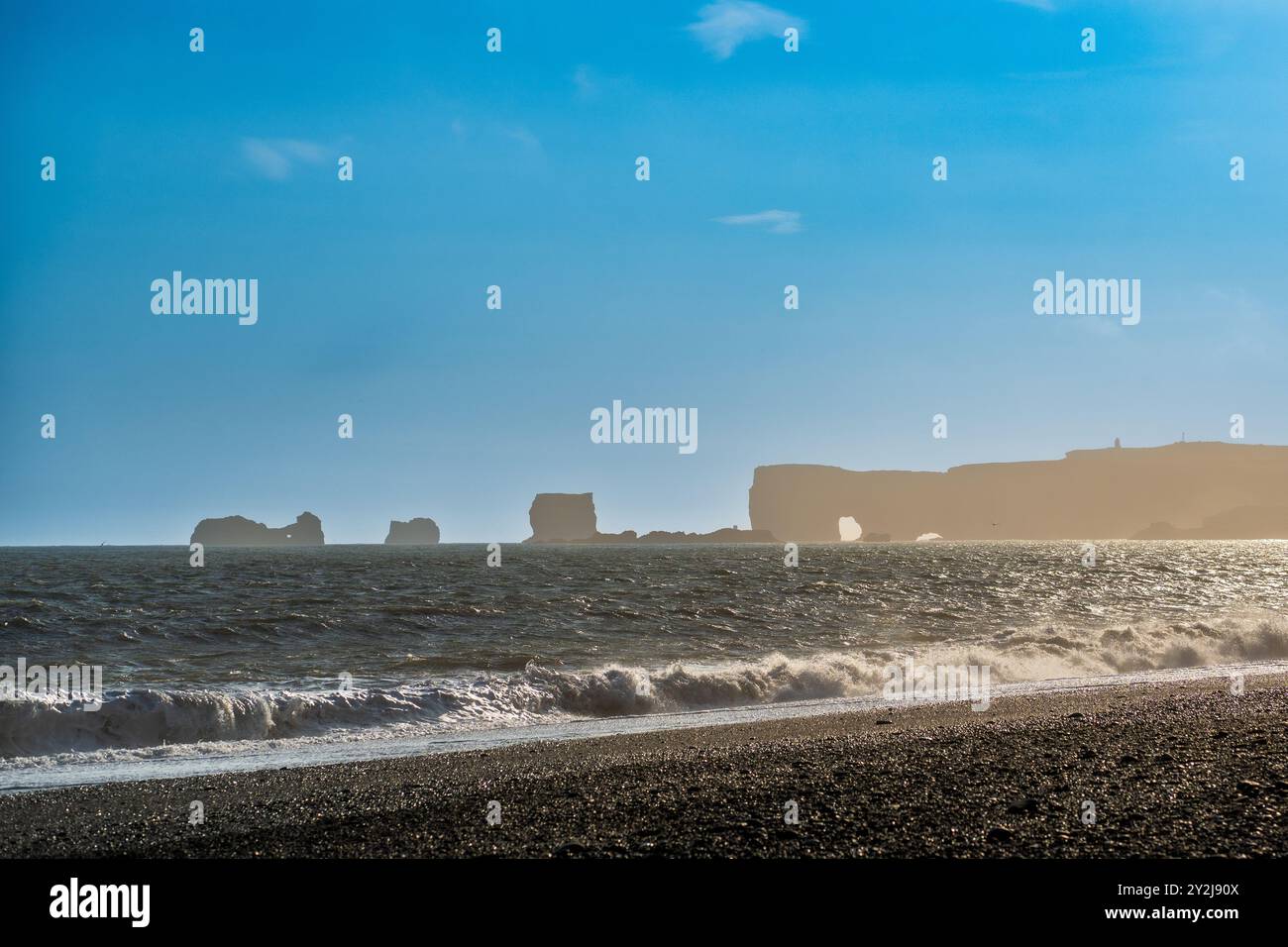 Montagne maestose con un massiccio ghiacciaio che scorre attraverso l'aspro paesaggio islandese sotto un cielo vibrante Foto Stock