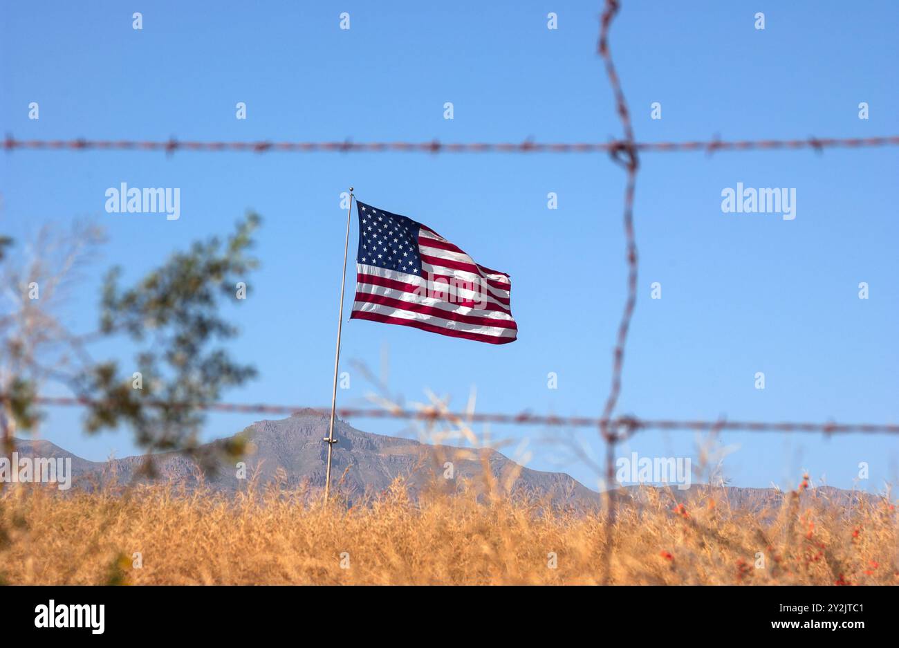 DESERTO DI SONORA, ARIZONA, Stati Uniti: Una bandiera americana ondeggia nella brezza, visto attraverso una recinzione di filo di ghisa nel deserto di Sonora in Arizona. © Lee Roth/ad Foto Stock