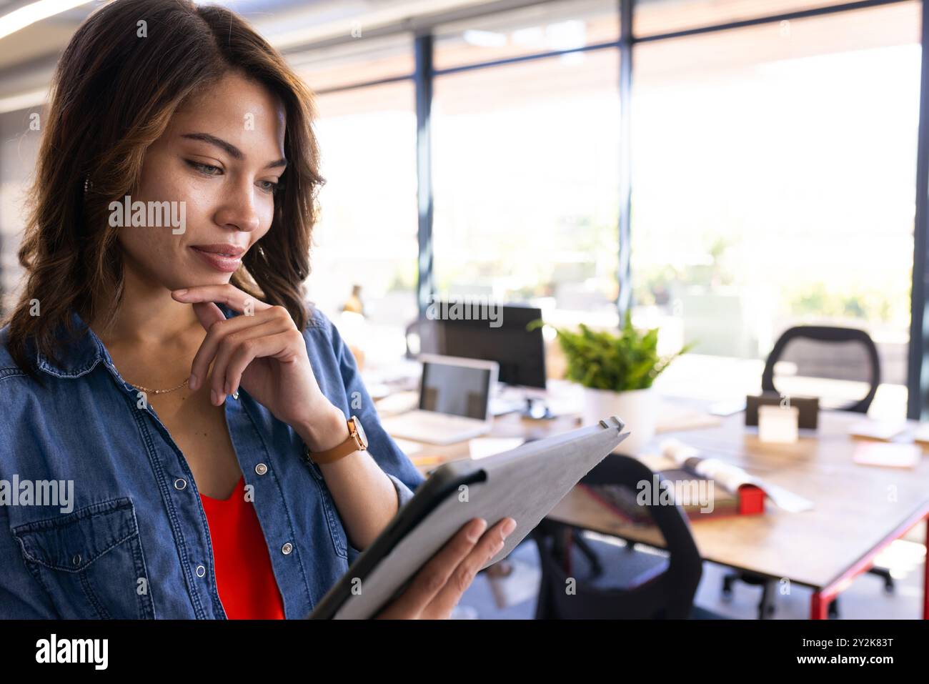 Che utilizza un tablet, una donna che esamina i progetti di interior design in un ufficio moderno Foto Stock