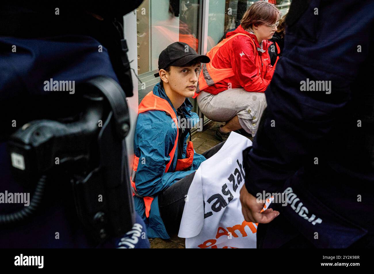 Un manifestante attende di essere prenotato dalla polizia durante la manifestazione. Un gruppo di attivisti di Ostatnie Pokolenie (l'ultima generazione) ha bloccato la strada Prosta. L'azione è una delle tante volte a promuovere opzioni di trasporto pubblico più economiche e più ampie. Il gruppo chiede che il governo sposti il 100% del denaro stanziato per le nuove autostrade verso il trasporto pubblico regionale e introduca un biglietto a basso costo da 50 PLN per il trasporto pubblico in tutta la Polonia. La serie di blocchi stradali si svolge nella settimana in cui gli studenti polacchi tornano a scuola. "Le persone devono chiedere il cambiamento" dicono, "Other Foto Stock