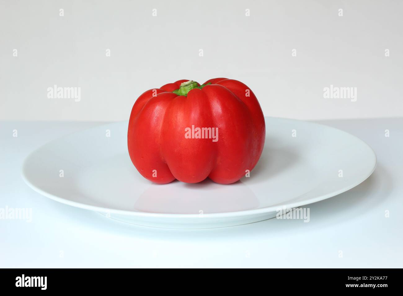 Pepe rosso crudo intero su piatto bianco Foto Stock