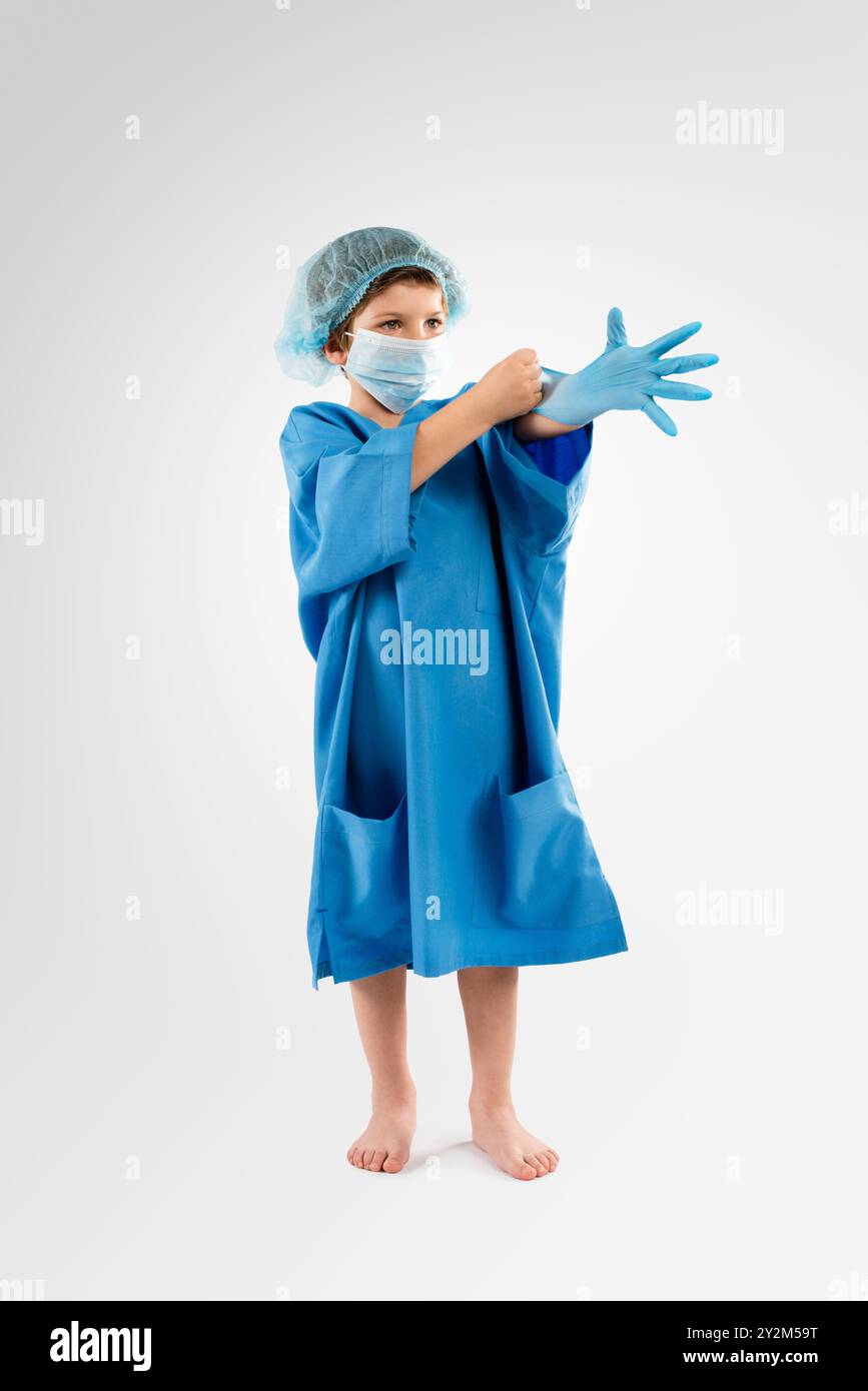 Bambino, scrub e guanti con maschera o uniforme in studio per chirurgia o assistenza sanitaria su sfondo bianco. Bambino, bambino o chirurgo junior con lattice Foto Stock