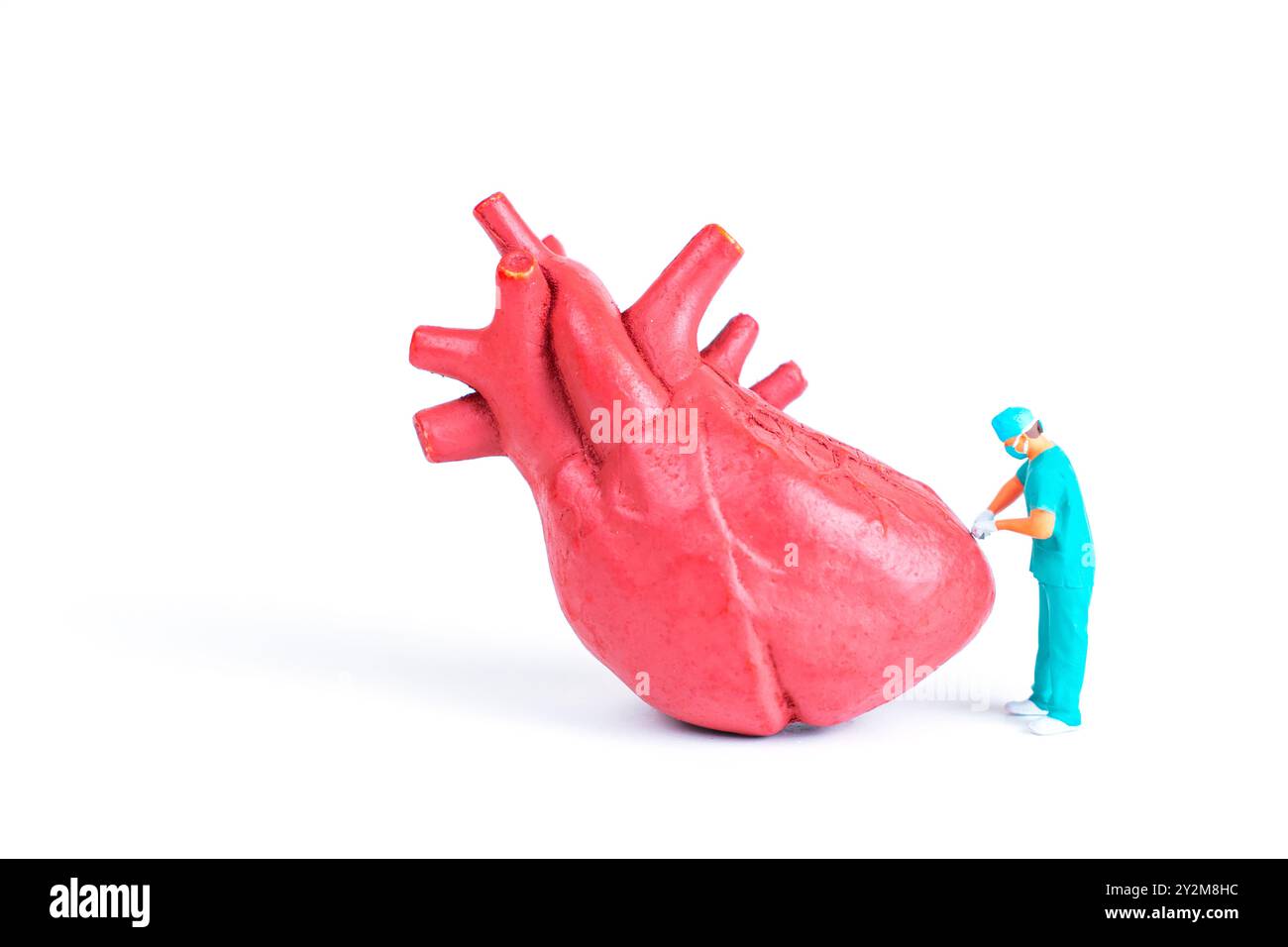 Piccolo chirurgo che lavora su un grande modello di cuore, illustrando l'intervento medico e temi sanitari. Foto Stock