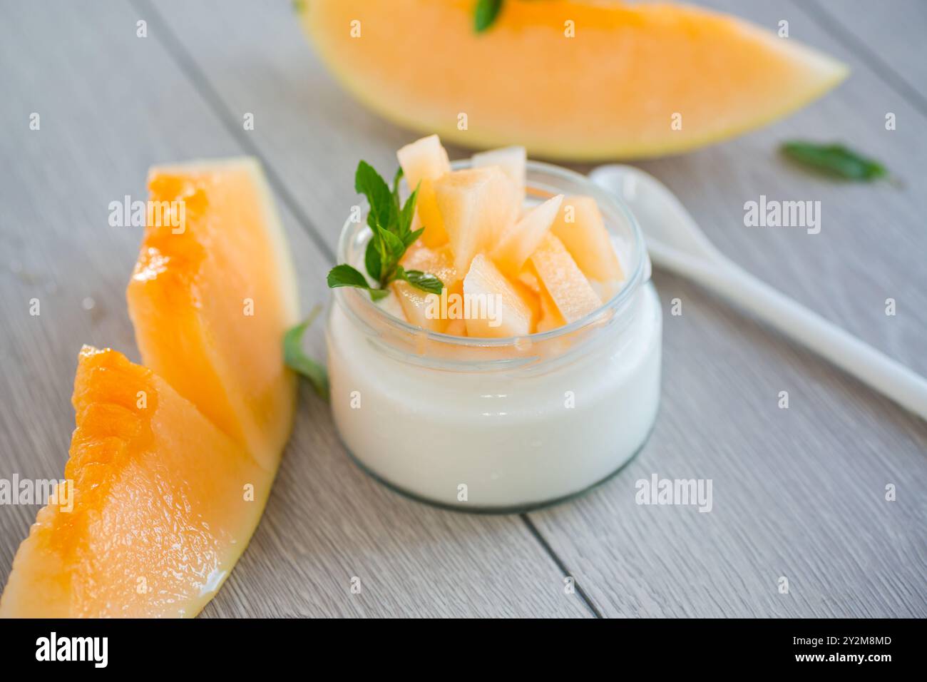 yogurt dolce fatto in casa in un barattolo con pezzi di melone maturo . Foto Stock