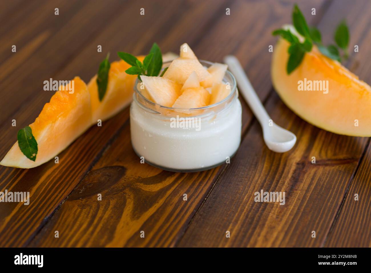 yogurt dolce fatto in casa in un barattolo con pezzi di melone maturo . Foto Stock