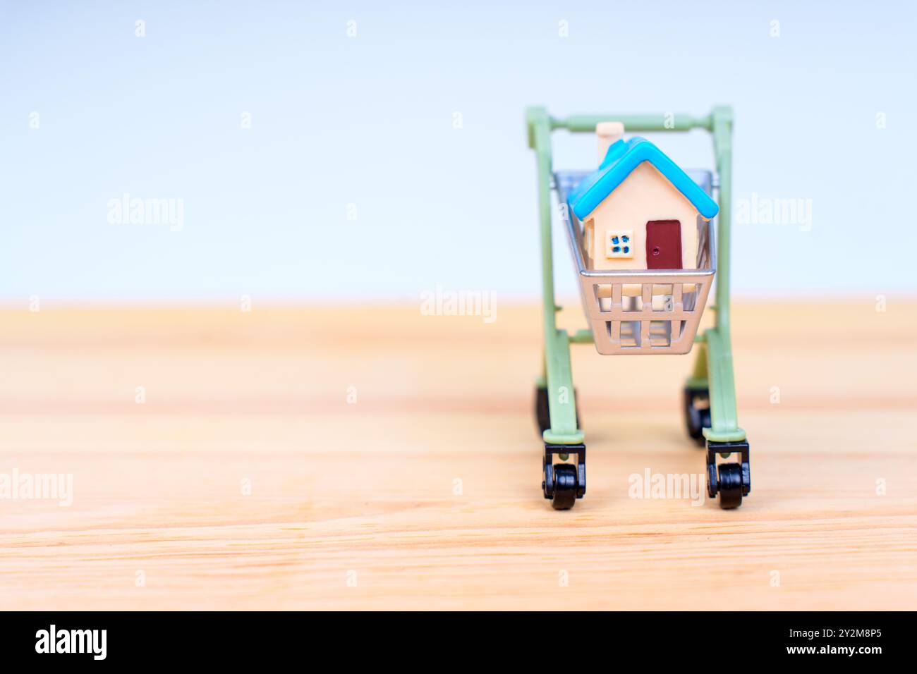 Modello di casa all'interno di un carrello su un tavolo di legno, che rappresenta l'intersezione delle tendenze abitative e dei consumatori. Foto Stock